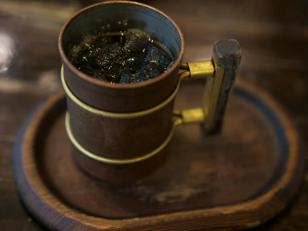 A metal drinking mug on a wooden table